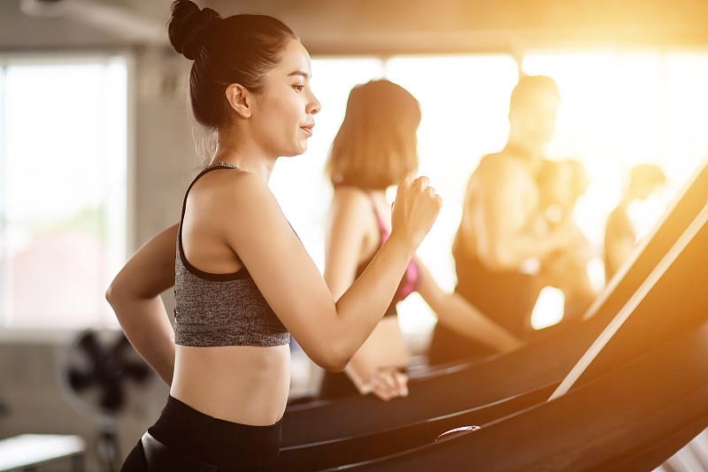 女人在健身房跑步机上跑步的侧视图图片素材