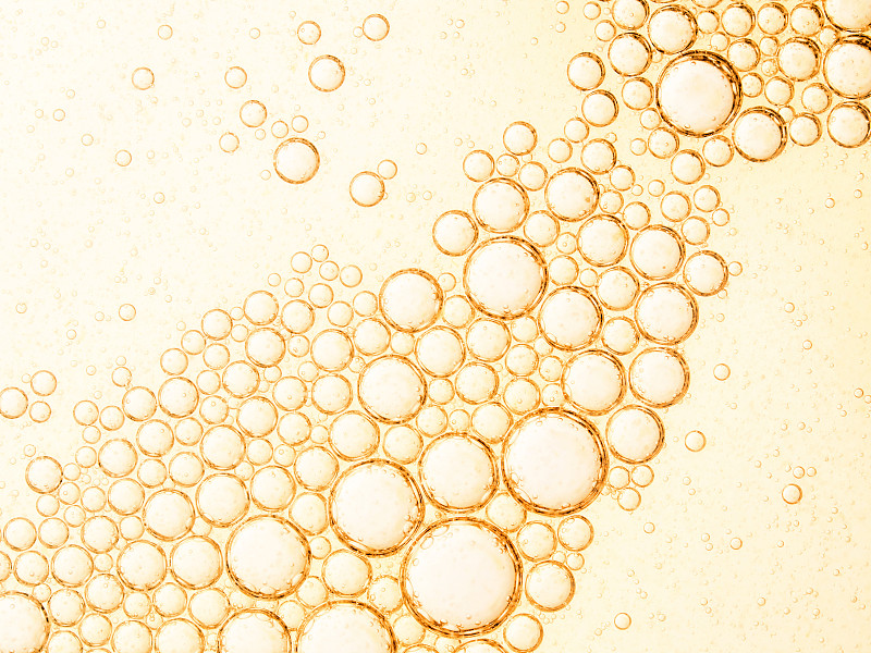 全框架抽象的形状和纹理形成的泡沫和滴油渍在黄色液体背景。图片素材