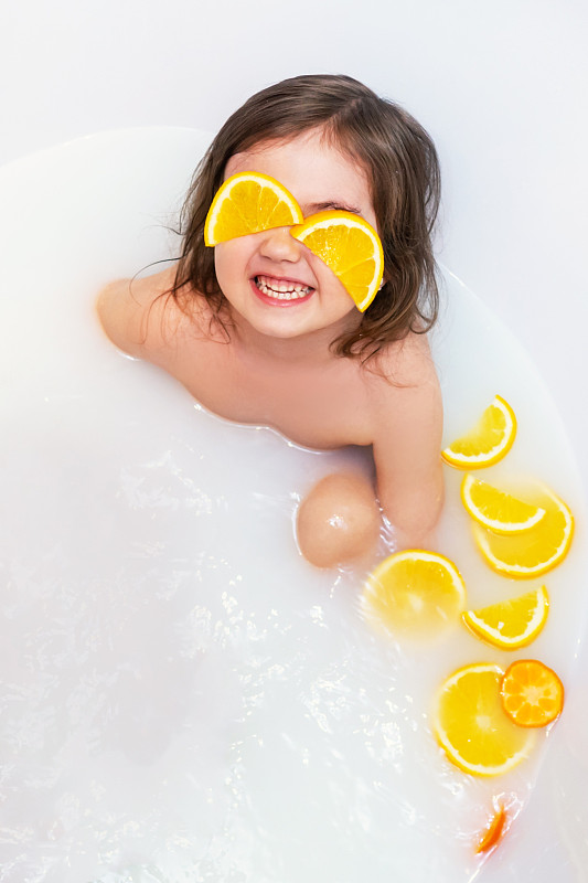 女婴用橘子洗牛奶浴。图片素材
