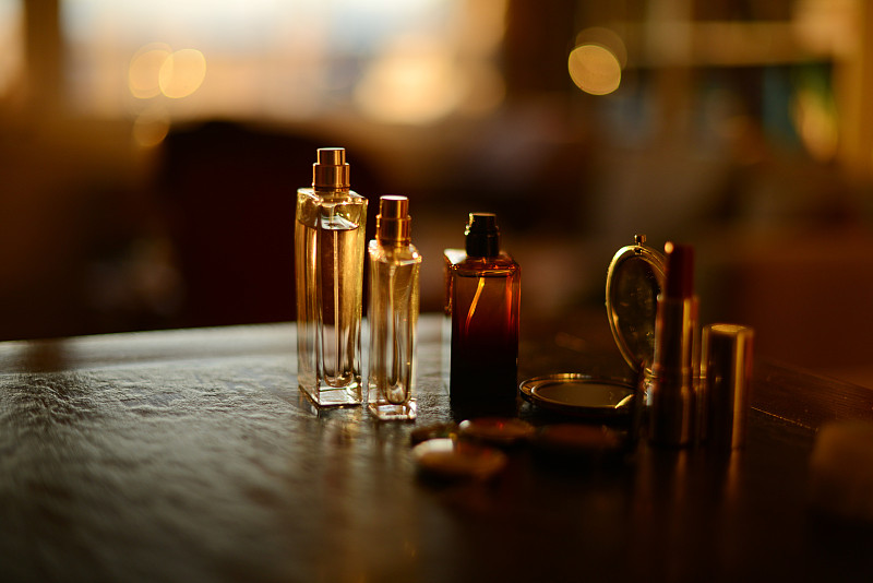 香水瓶，项链和化妆品在美丽的金色阳光下的黑色背景图片素材