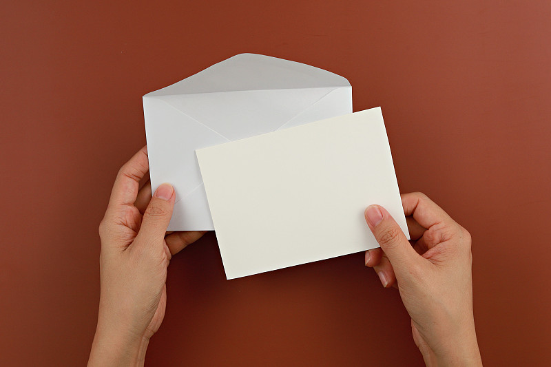 裁剪手握信封在棕色的背景图片素材