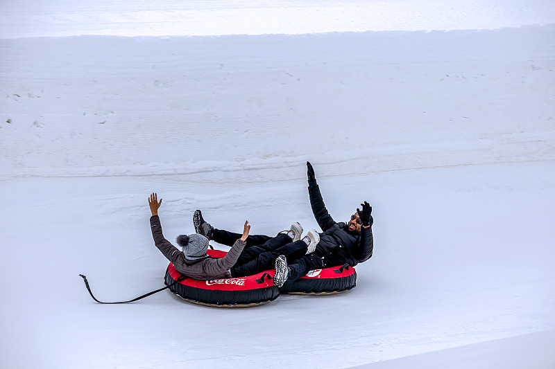 在科罗拉多州温特公园，一对夫妇在油管雪橇上从山上滑下来图片下载