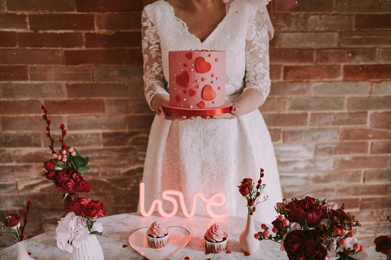 新娘的手拿着粉红色的新娘蛋糕图片素材