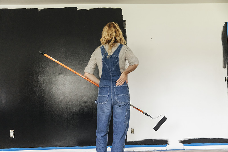 女人站在家里看着粉刷的墙图片素材