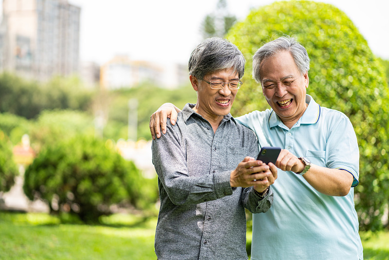 一对台湾父子在公园里玩智能手机图片下载