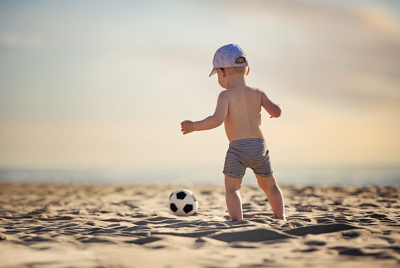 小男孩在海滩上玩足球图片下载