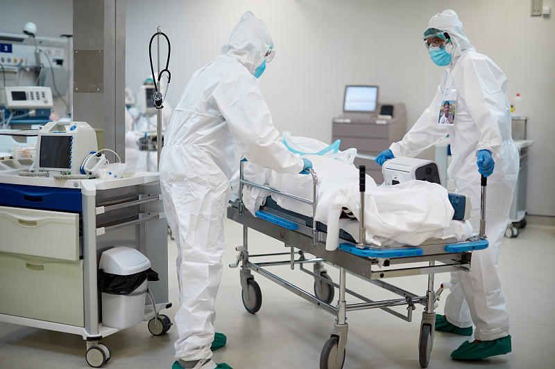 冠状病毒感染的医院工作人员穿着防护服推着担架。图片下载