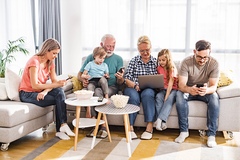 多代家庭在家中使用无线技术。图片素材