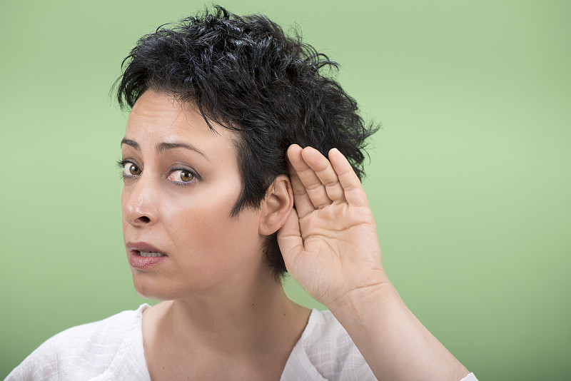 成年女人听不到什么，就把手放在耳朵后面。图片下载