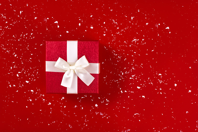 红色礼盒上的红色假日雪背景。图片素材