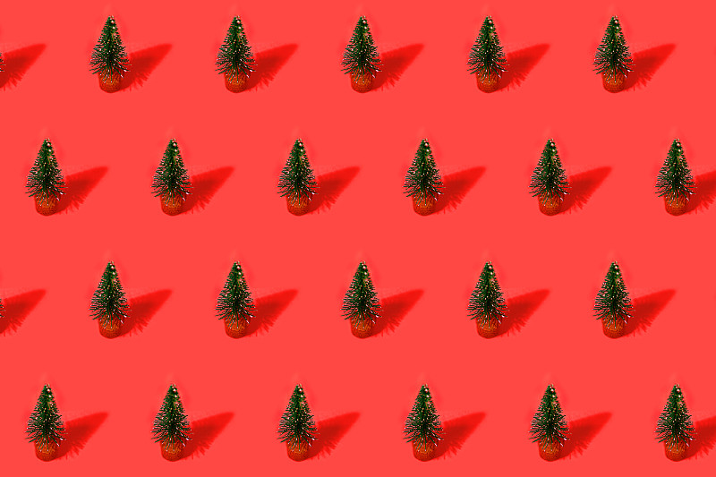 红色背景上的绿色圣诞树做成的节日图案。图片素材