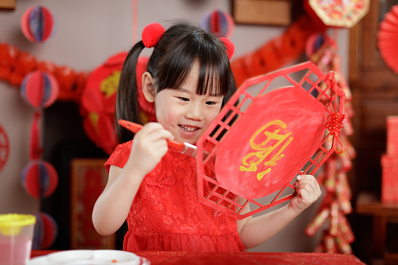 年轻的中国女孩为庆祝中国新年制作传统的中国幸运贺卡图片下载