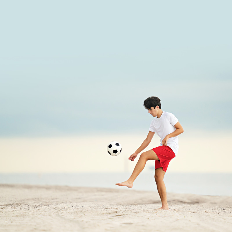佛罗里达州迈阿密海滩上，一名少年在玩足球杂耍图片下载