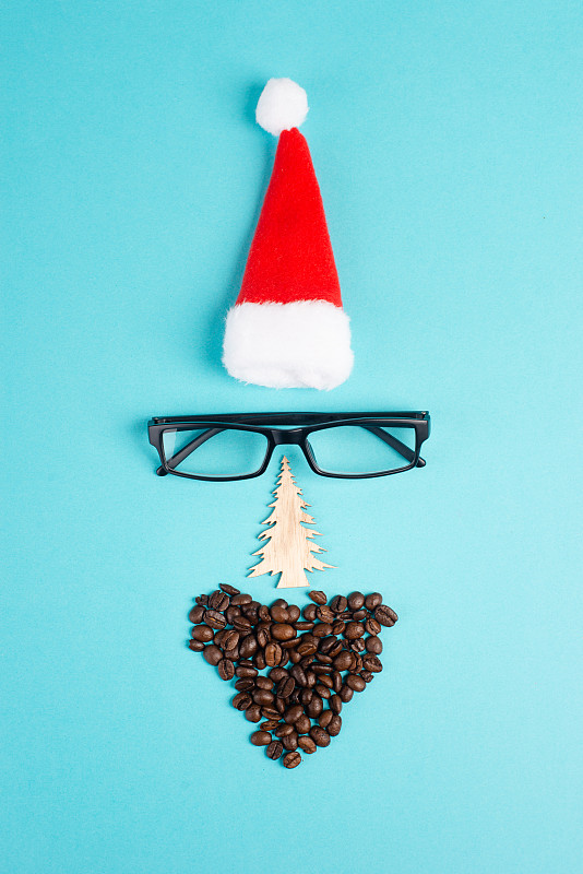 圣诞季，红色的圣诞老人帽，眼镜，胡子上的咖啡豆，搞笑的脸，冬天的时光，节日贺卡，蓝色的背景图片下载