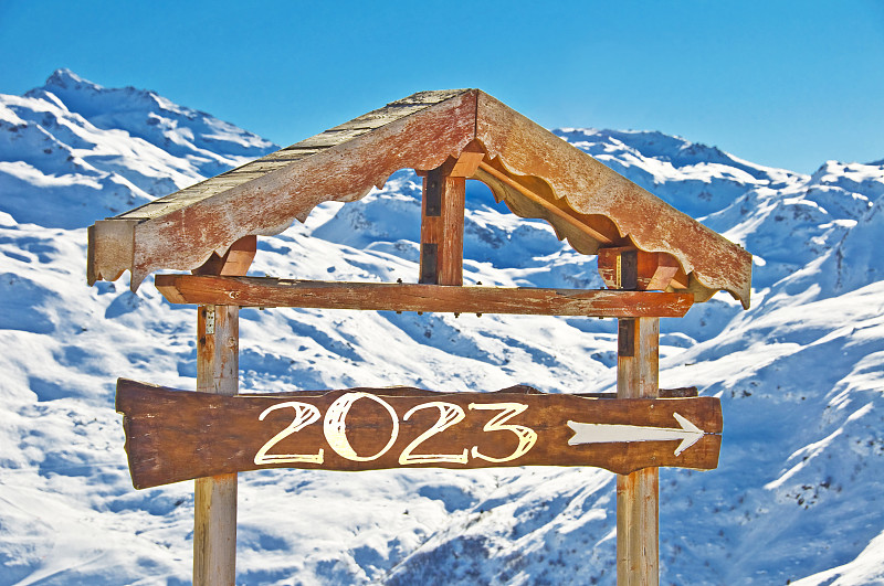 木牌上写着2023年方向牌，背景是雪山风景，滑雪过年卡图片下载