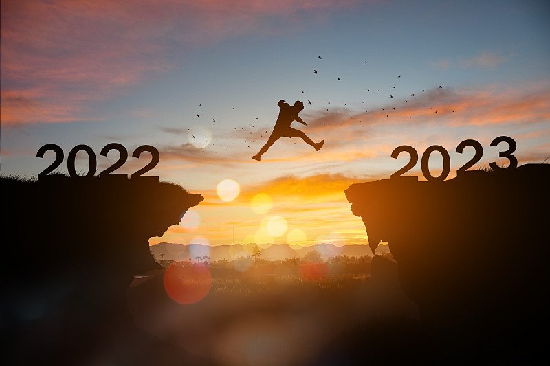 人的剪影在日落时跳到2023年的新年。图片下载