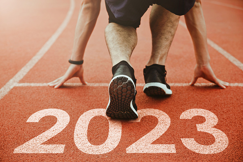 2023年新年快乐，2023年象征着新的一年的开始。一名男子正准备在刻着2023年的跑道上跑步。成功的目标。为新年做准备图片下载