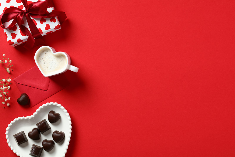 情人节的背景与礼盒，心形糖果，咖啡杯，红信封和鲜花的红色背景。情人节贺卡模板。平铺，俯视图图片下载