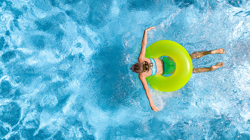 活跃的年轻女孩在游泳池空中俯瞰上方，青少年放松和游泳在充气环甜甜圈，并在家庭度假，热带度假胜地的水里玩得很开心图片下载
