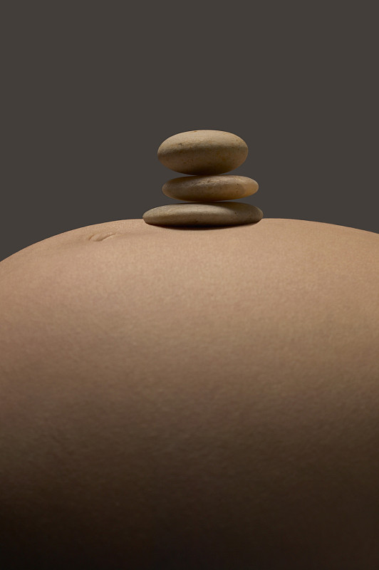 一个孕妇的胃的特写，上面有三个鹅卵石图片素材