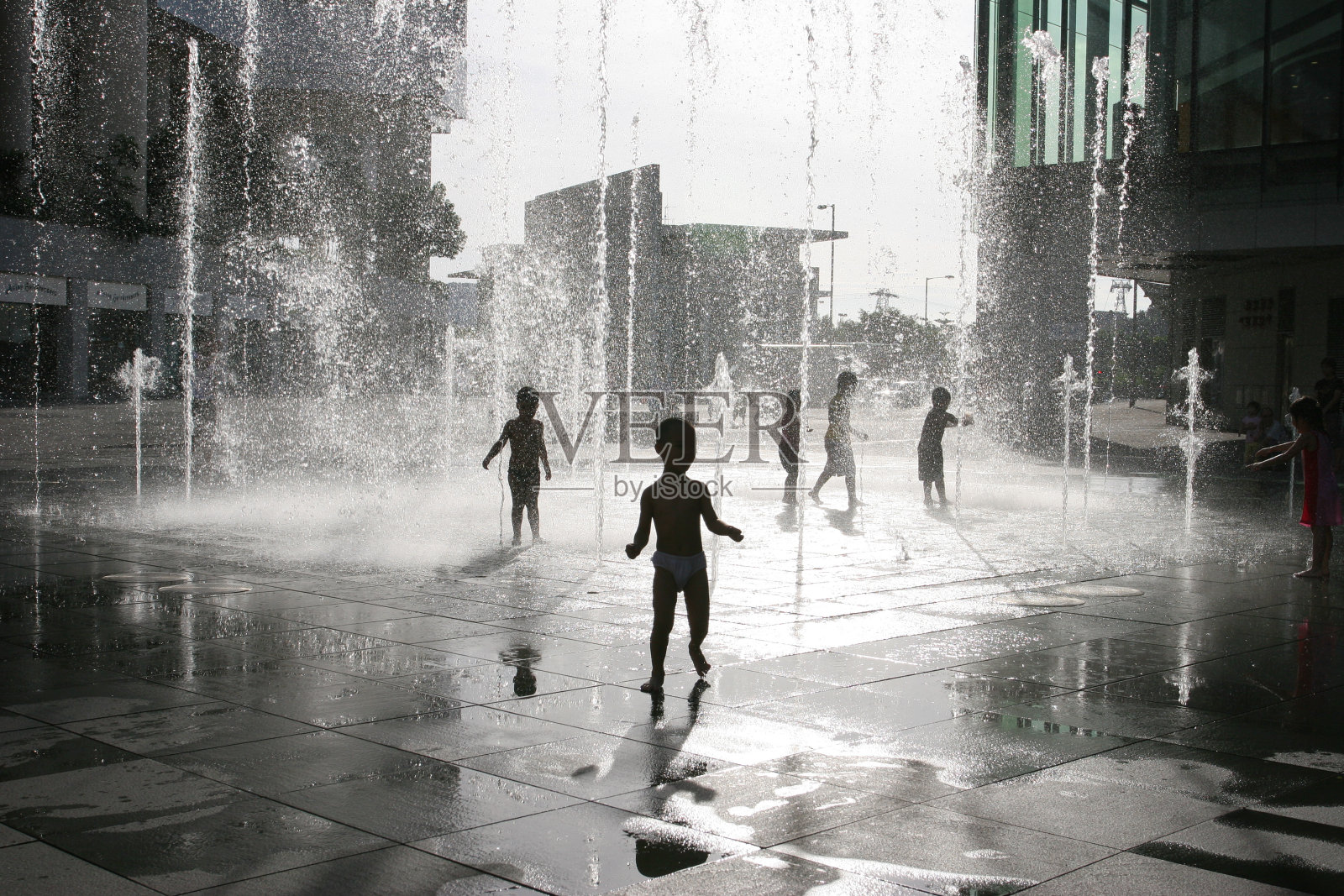 夏天，孩子们在城市的喷泉上玩耍照片摄影图片