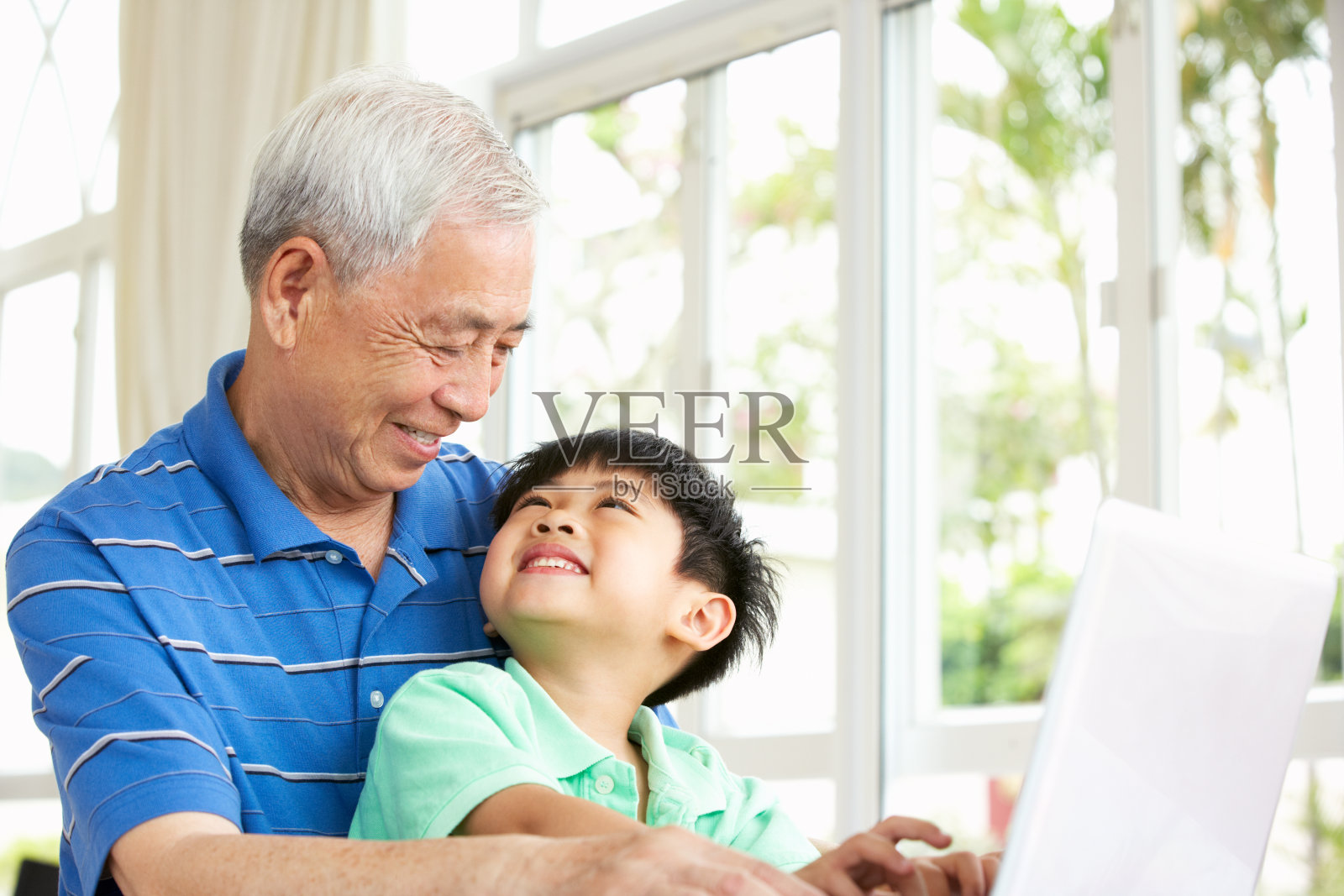 中国爷爷和孙子坐在书桌前使用笔记本电脑照片摄影图片