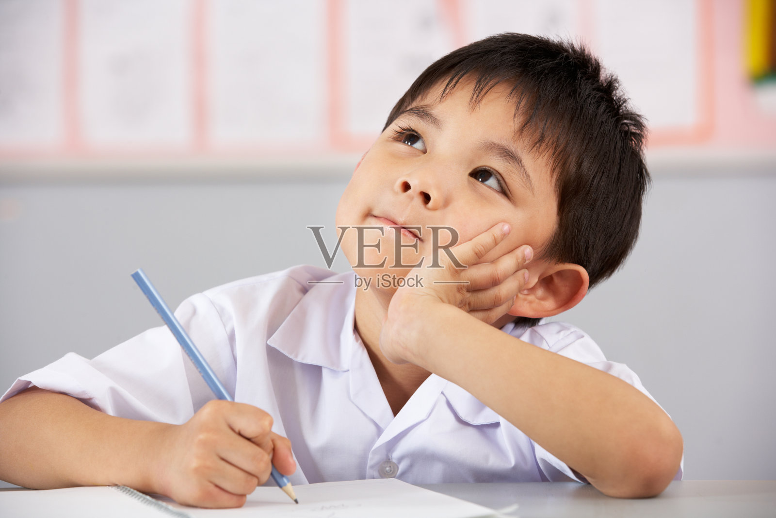 中文教室里，年轻的男学生坐在书桌前思考照片摄影图片