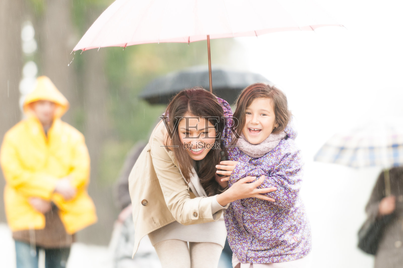 母亲和孩子在雨伞下的雨天。照片摄影图片
