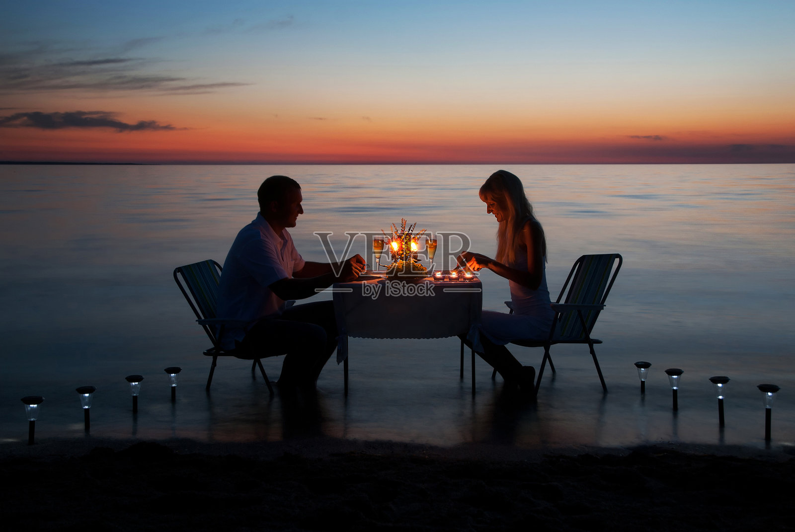 年轻夫妇在海滩上用蜡烛共进浪漫晚餐照片摄影图片