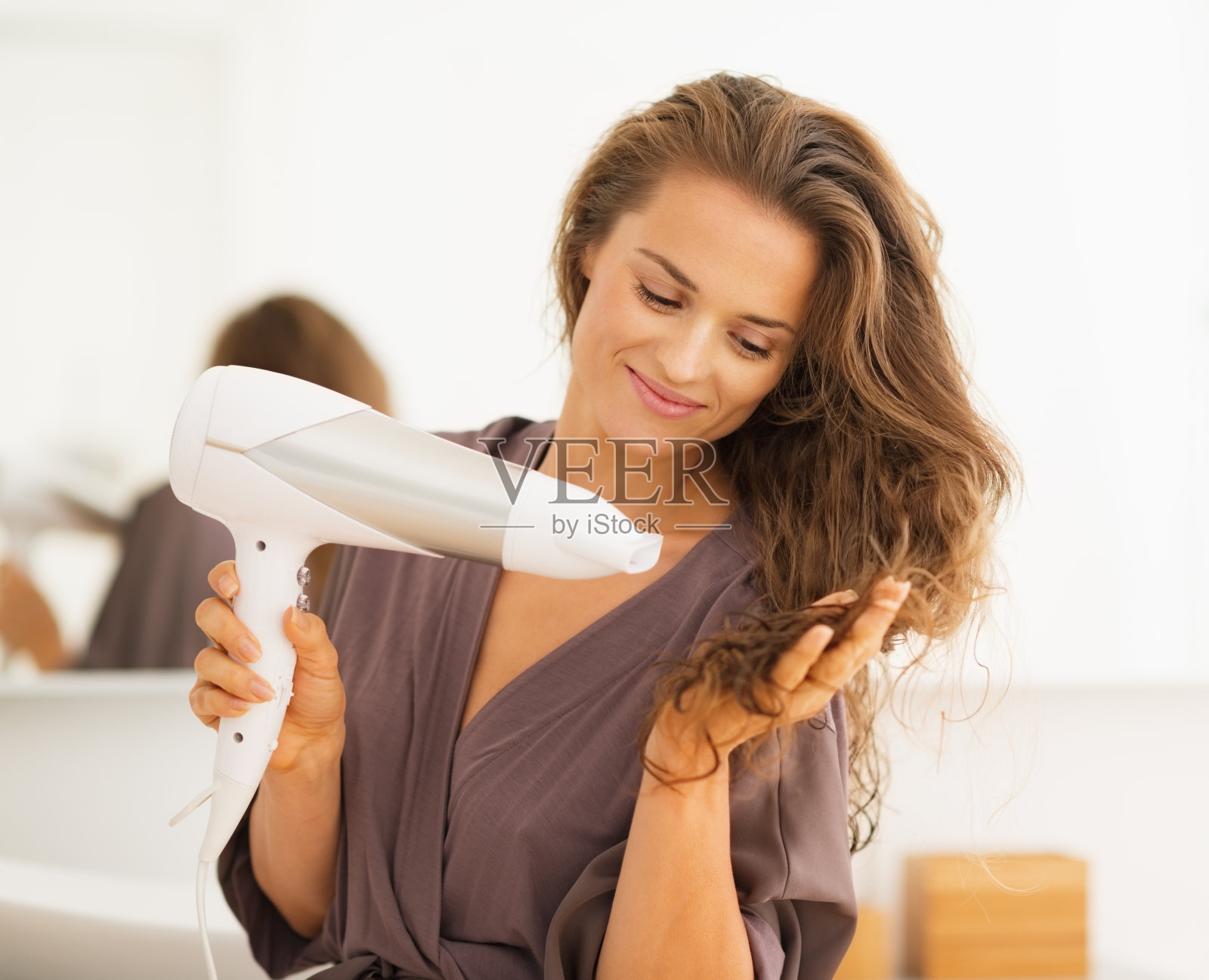 快乐的年轻女子在浴室吹干头发照片摄影图片