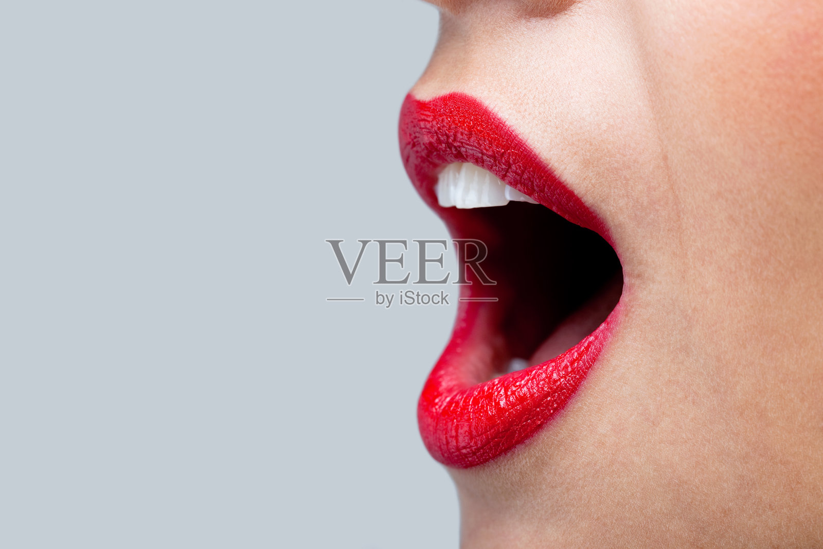 女人的嘴张得大大的，涂着红色的口红。照片摄影图片