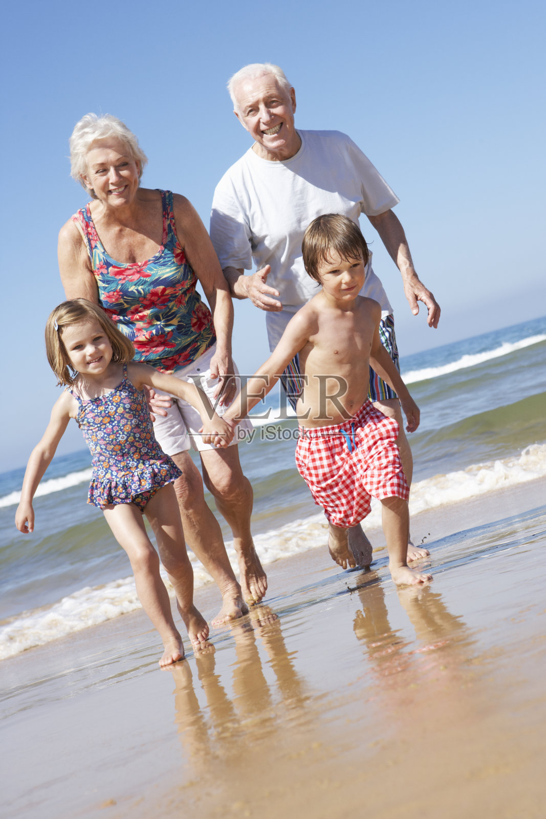 祖父母和孙辈在海滩上跑步照片摄影图片