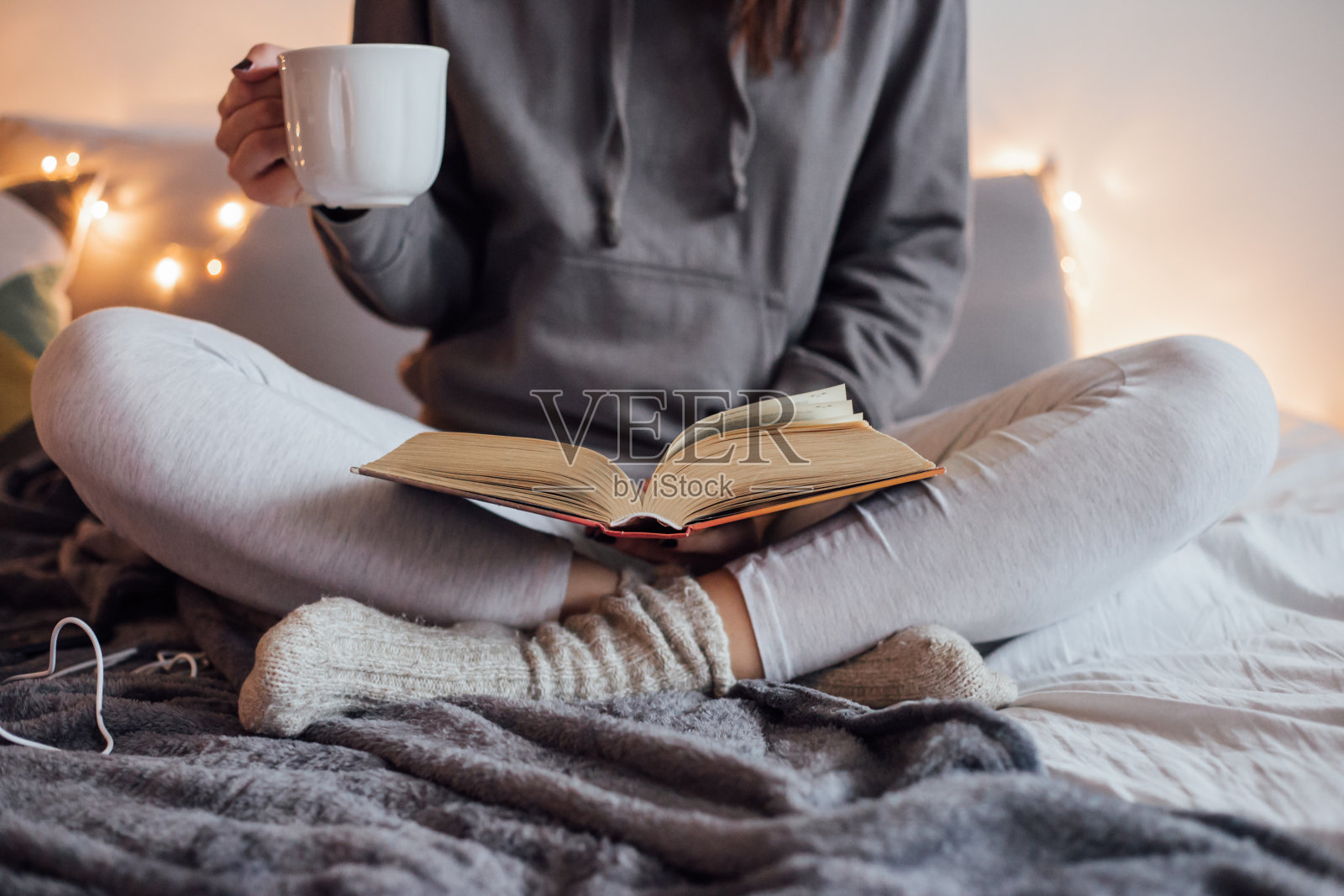 女孩喝着热茶，在床上看书照片摄影图片