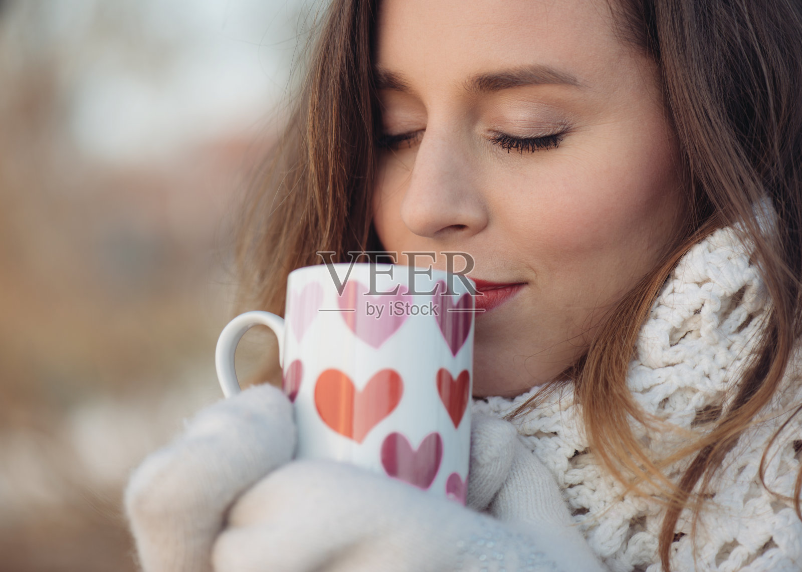 冬天的女人拿着杯子取暖。可爱的年轻女子在户外用装饰好的马克杯喝茶或喝咖啡。照片摄影图片
