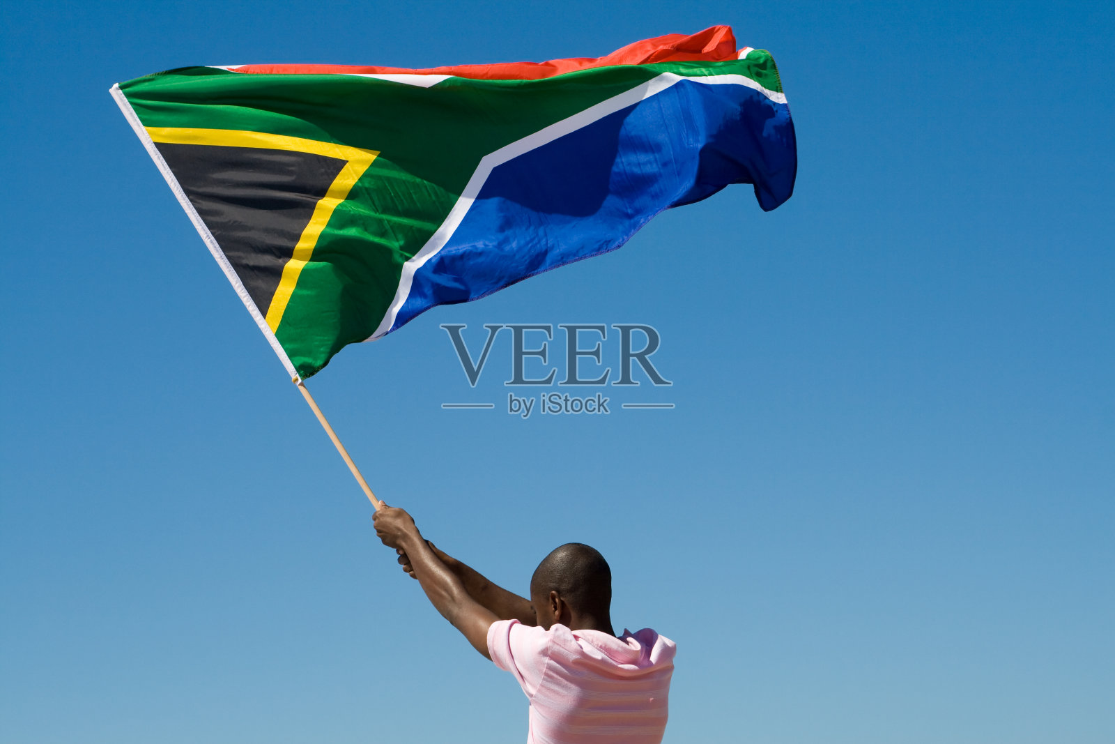 一个在晴朗的天空中挥舞南非国旗的男人的后视图照片摄影图片