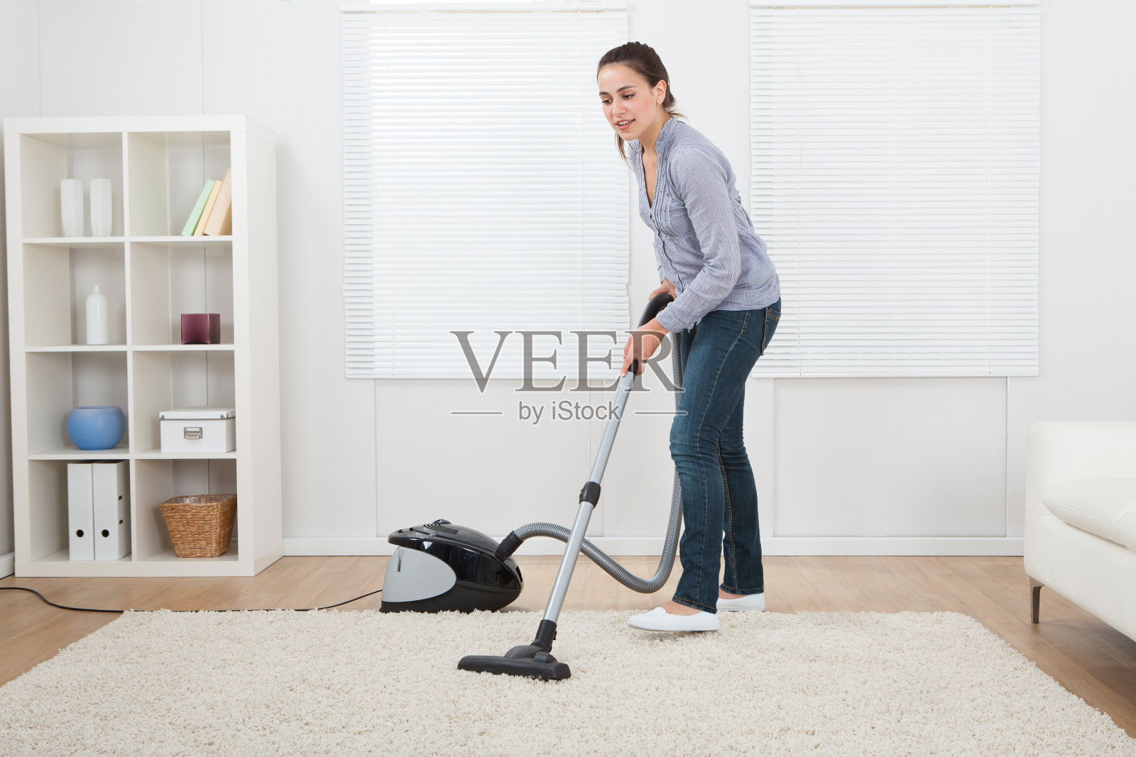 在家用吸尘器清扫地毯的女人照片摄影图片