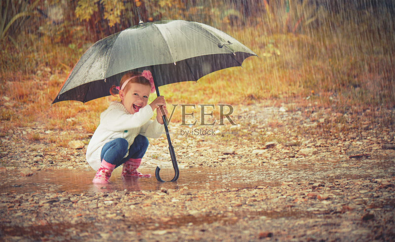 快乐的小女孩撑着伞在雨中洒落大自然照片摄影图片