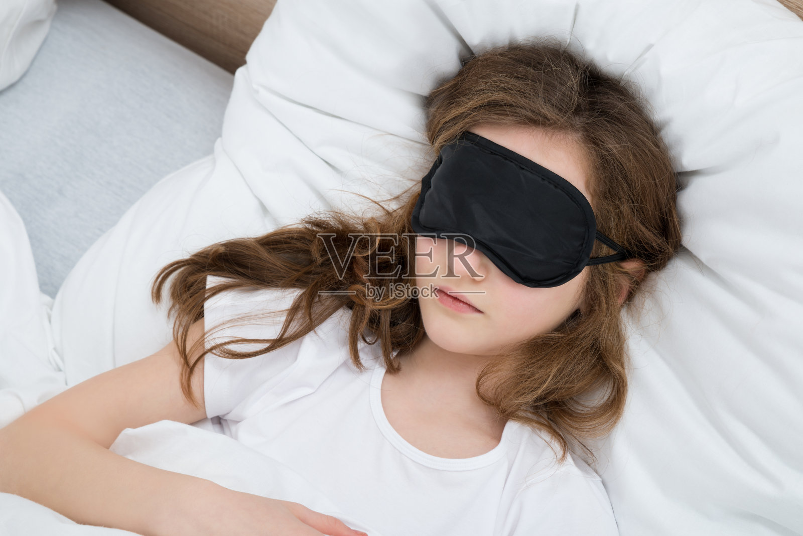 戴着睡眠面罩睡在床上的女孩照片摄影图片