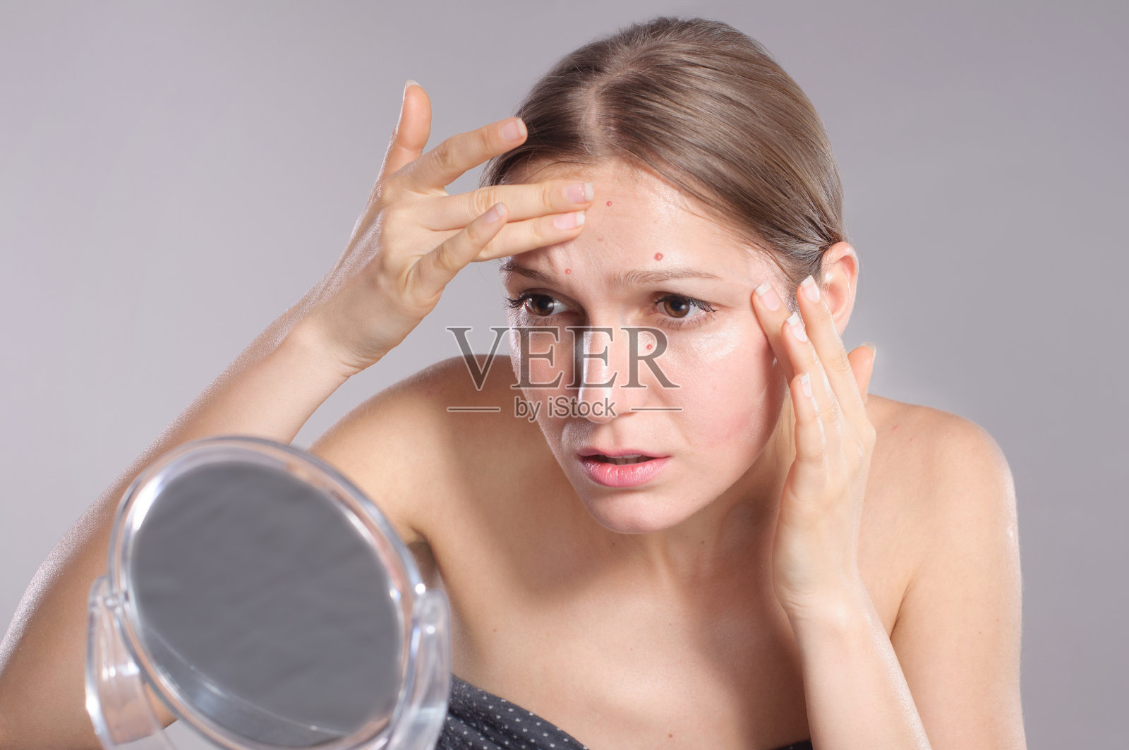 一个年轻女子在镜子前捏捏脸上的粉刺照片摄影图片