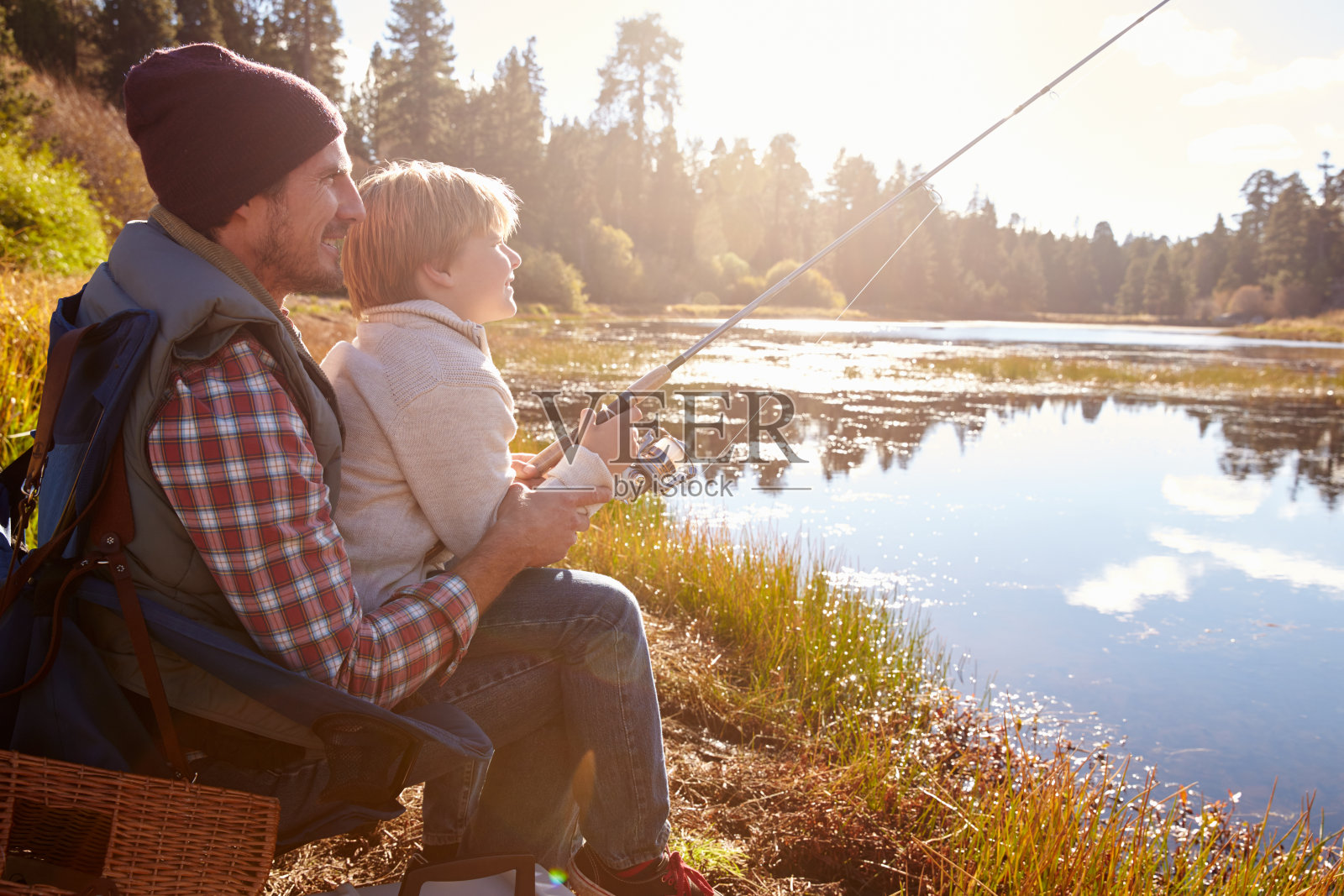 父亲坐在湖边教儿子钓鱼照片摄影图片