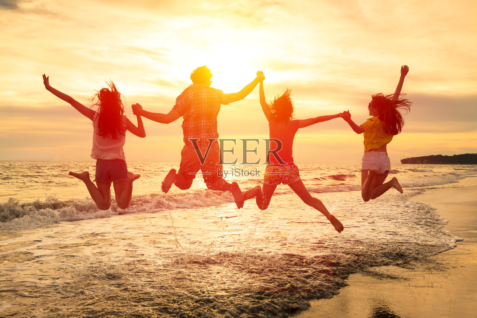 一群快乐的年轻人在海滩上蹦蹦跳跳照片摄影图片