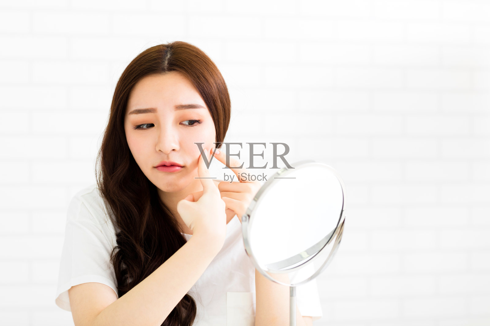 一个年轻女子在镜子前捏捏脸上的粉刺照片摄影图片
