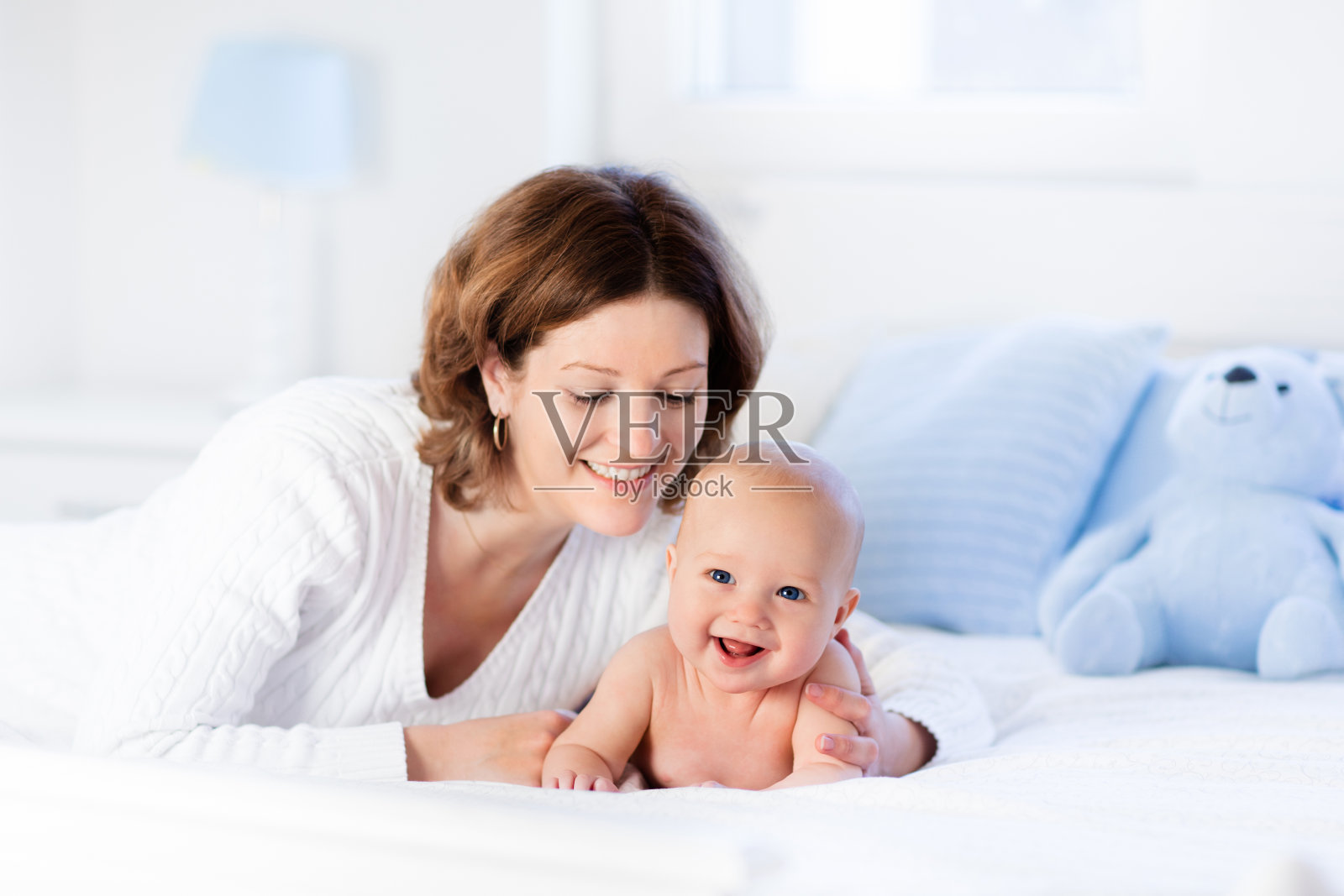 妈妈和婴儿在白色的床上照片摄影图片