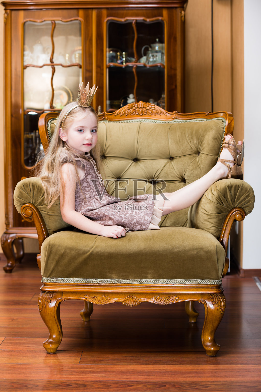 金发小女孩戴着皇冠站在椅子上照片摄影图片