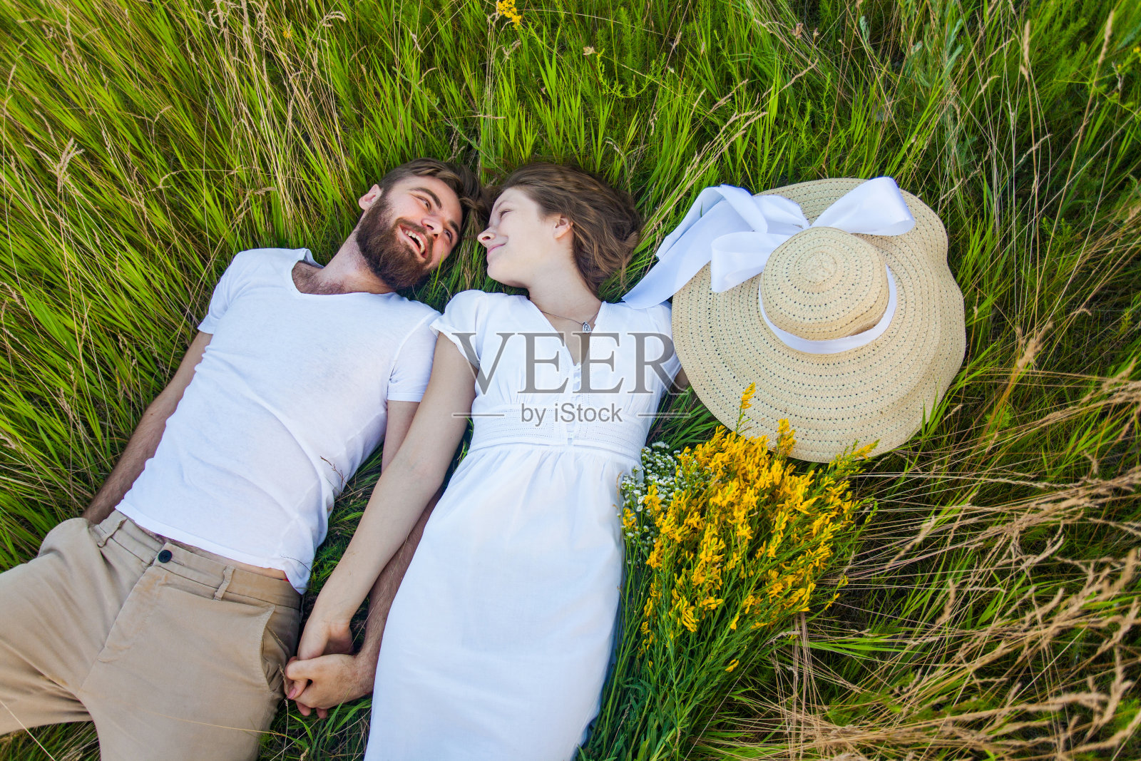快乐的年轻夫妇在爱躺在草地上。照片摄影图片