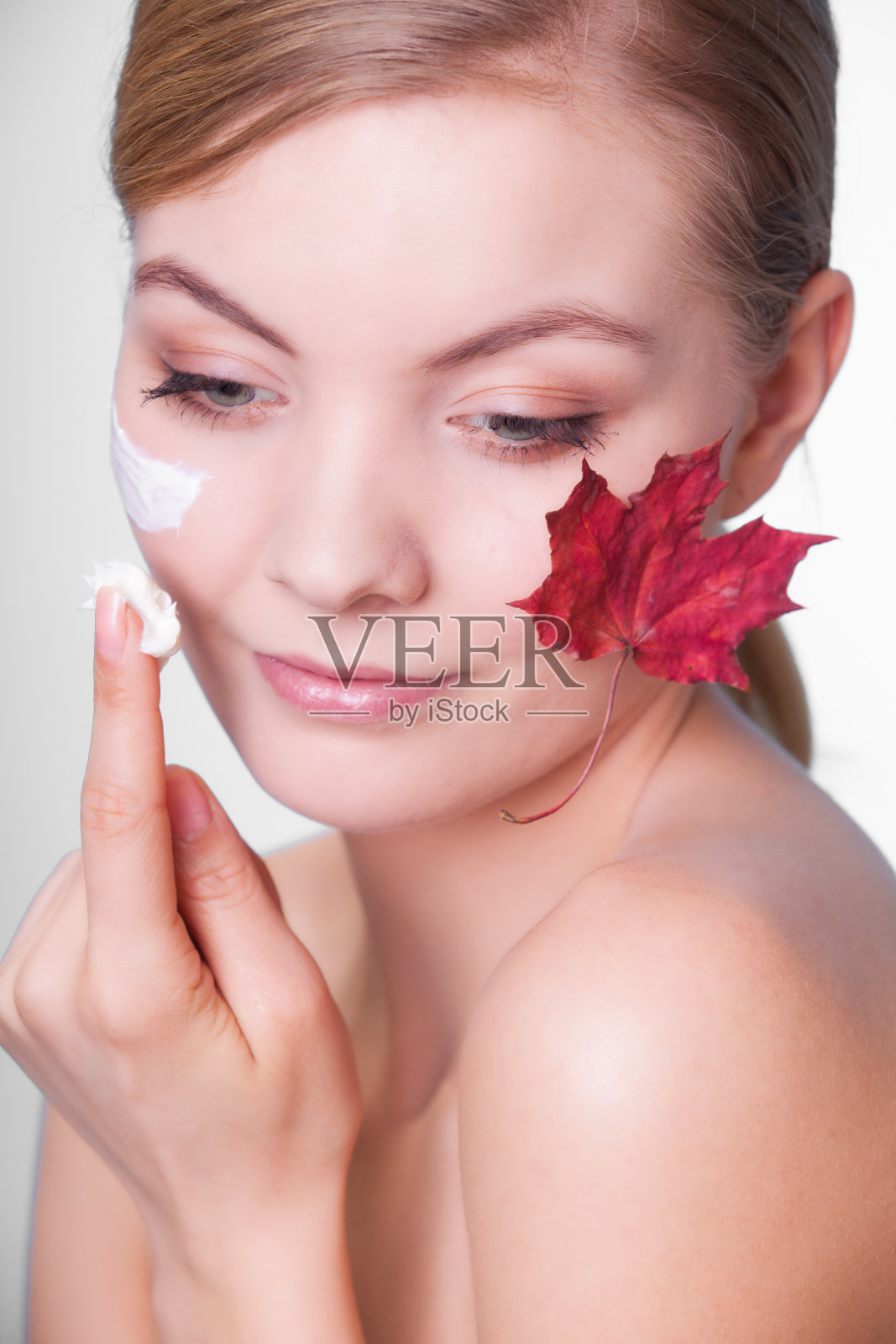 皮肤护理。年轻女子的脸上带着枫叶。照片摄影图片