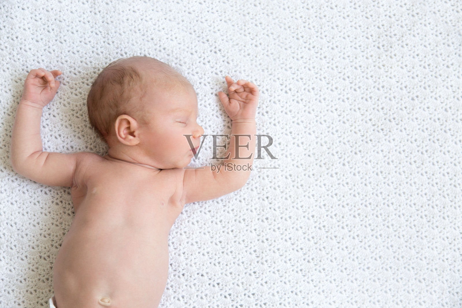 新生儿在白毯子上打盹照片摄影图片