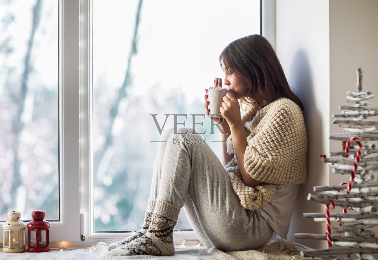 年轻漂亮的女人坐在窗台上喝着热咖啡照片摄影图片
