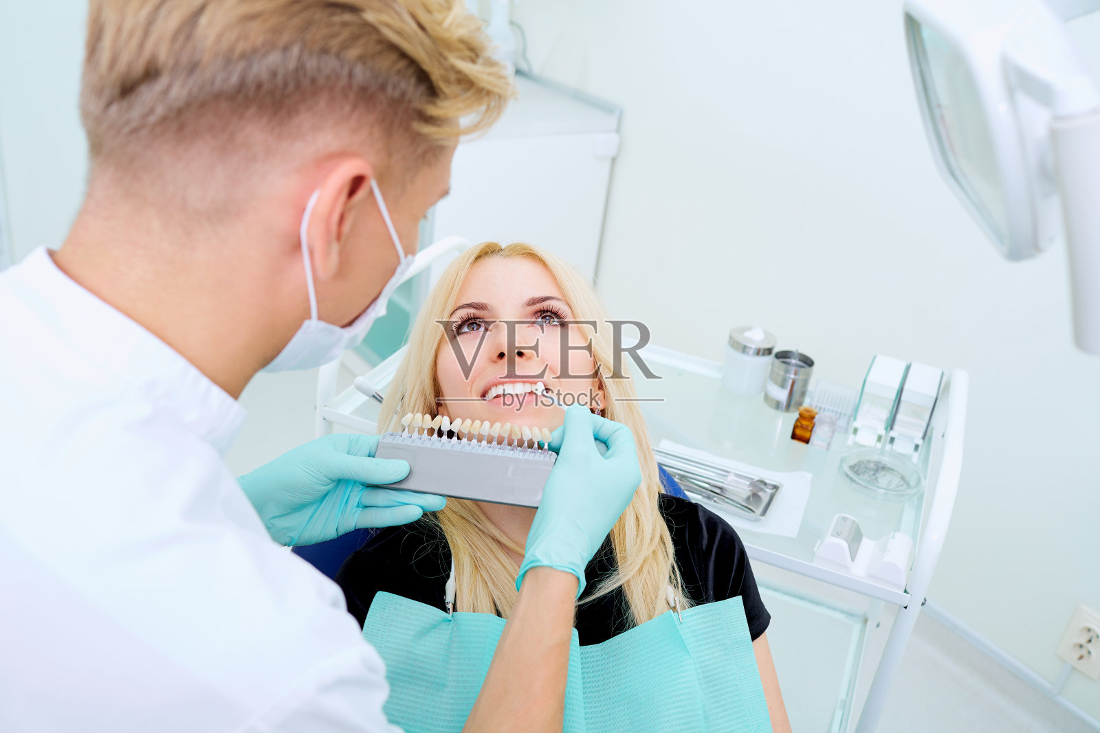 牙科医生尽量选择牙齿的颜色和病人照片摄影图片