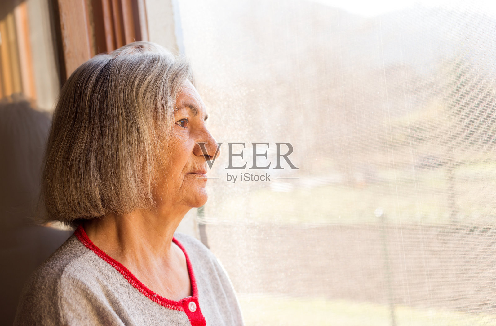 老女人孤独的老透过窗户看照片摄影图片